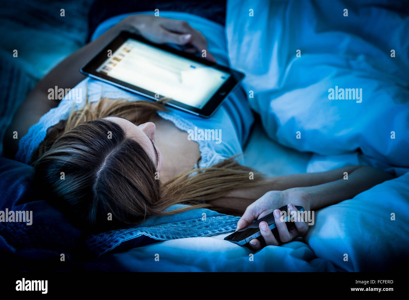 Frau mit einem digitalen Tablet und Smartphone in der Nacht. Stockfoto