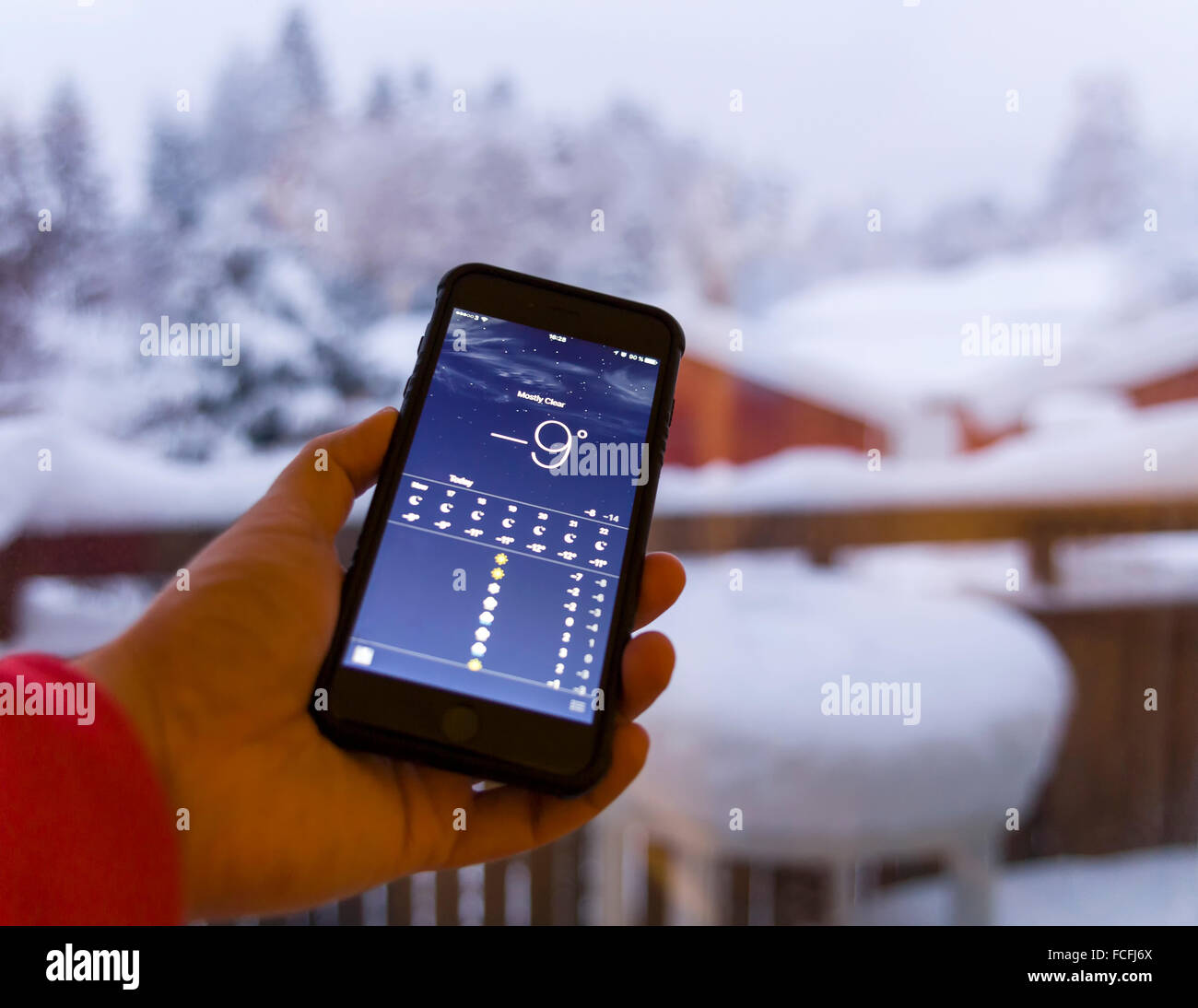 Man Kontrolle Wettervorhersage auf dem Smartphone vor verschneiten Winterlandschaft Model Release: Ja. Property Release: Nein. Stockfoto