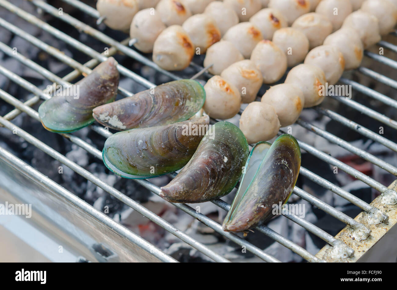 Frikadellen auf Metall Spieße und grüne Muscheln auf einem Grill gegrillt Stockfoto