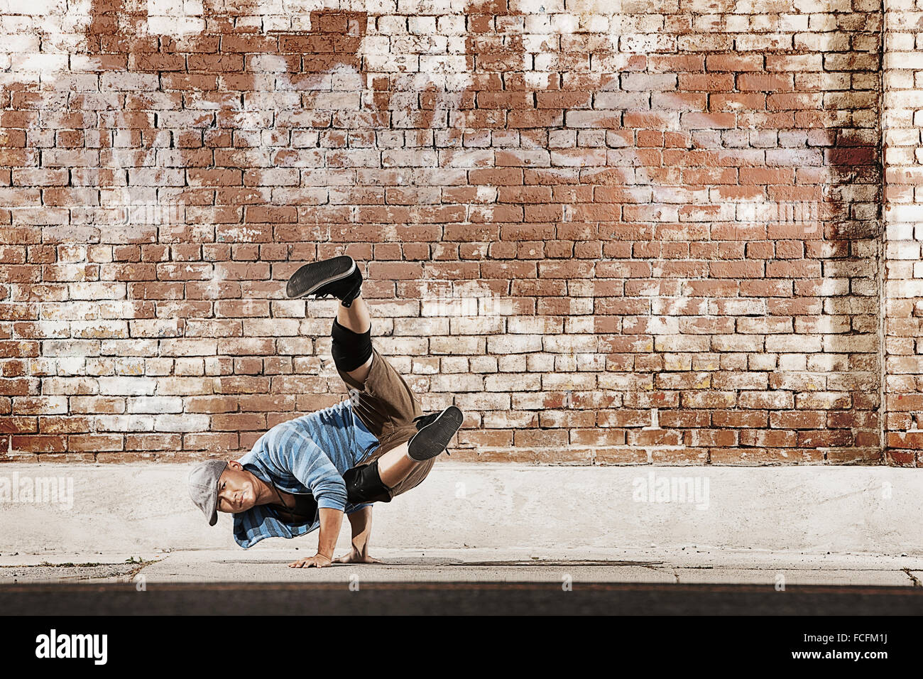 Ein junger Mann eine Breakdance zu tun bewegen balancieren auf seinen Händen auf der Straße einer Stadt. Stockfoto