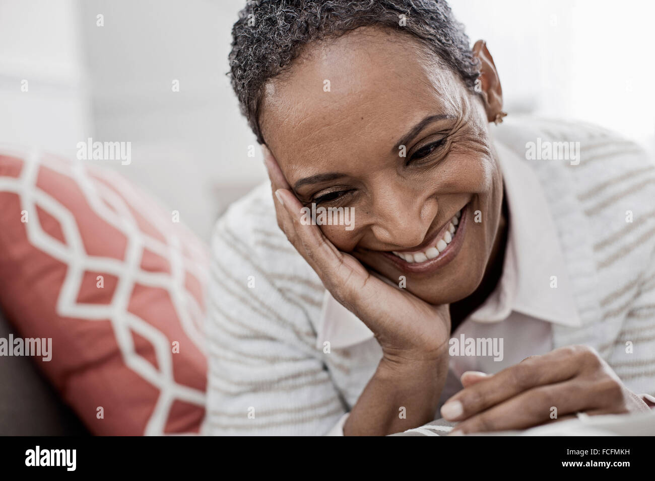 Eine Frau zu Hause liegen auf dem Sofa und ruht ihr Kinn auf ihre Hände. Stockfoto