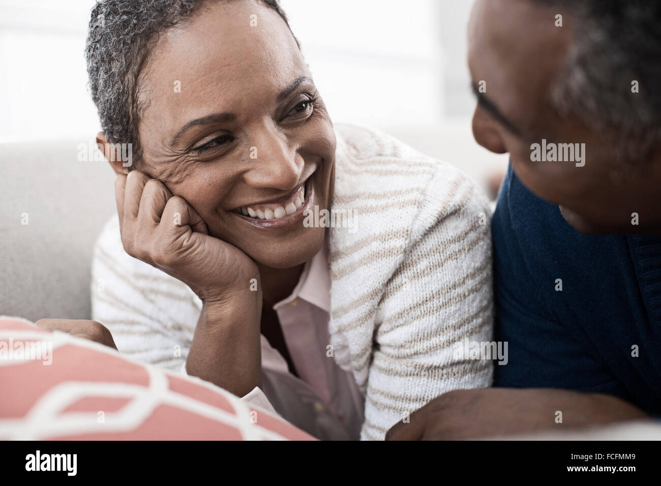 Ein paar, Mann und Frau liegend auf dem Bauch lachen einander an. Stockfoto