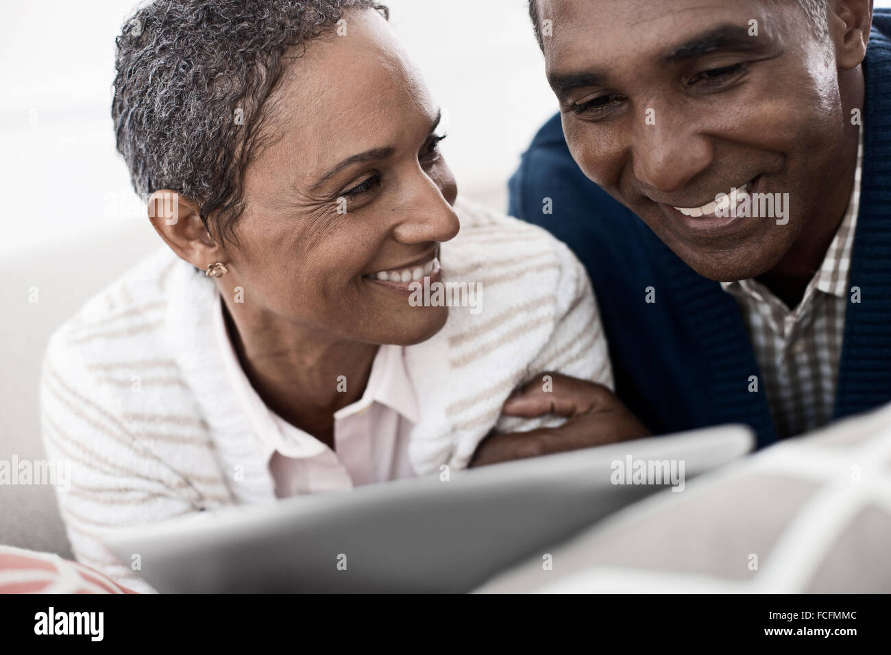 Ein paar, Mann und Frau auf dem Bauch liegend eine digitale-Tablette teilen. Stockfoto