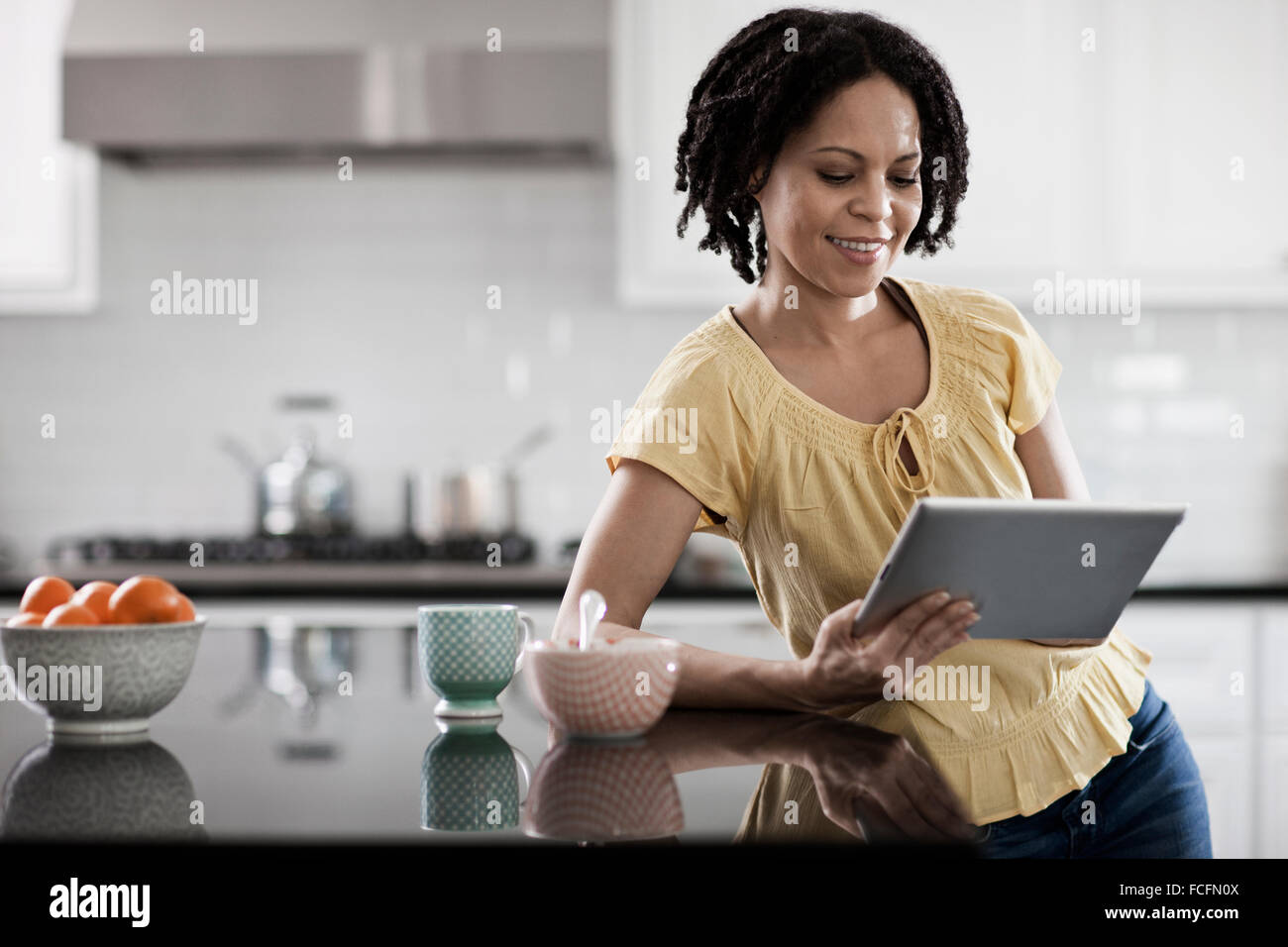 Eine Frau mit einem digitalen Tablet in ihrem Haus. In der Küche stand. Stockfoto