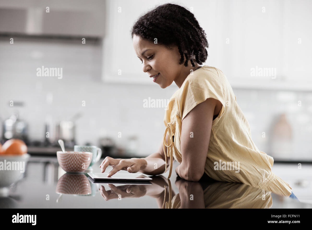 Eine Frau mit einem digitalen Tablet in ihrem Haus. In der Küche stand. Stockfoto