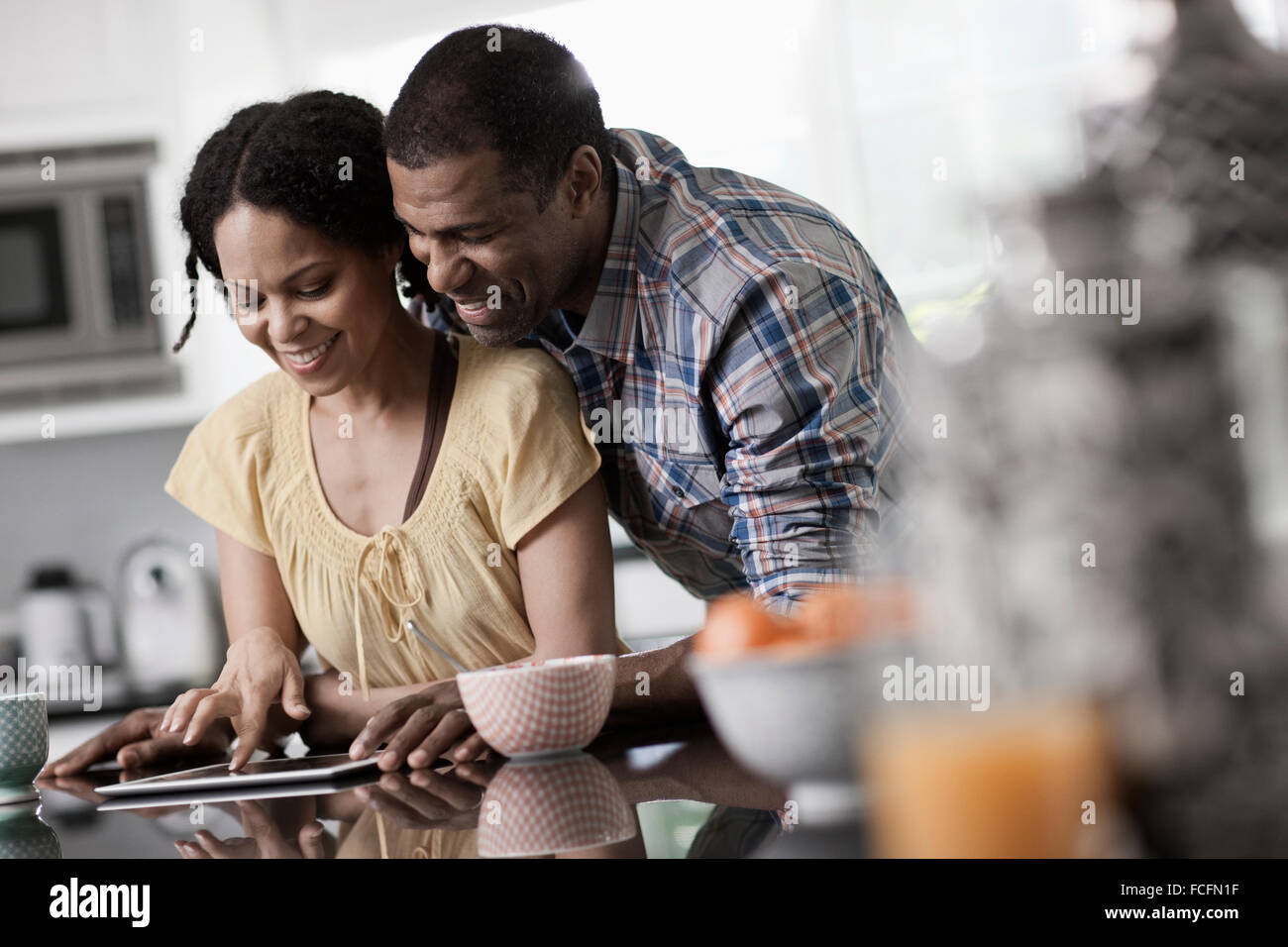 Ein Mann und eine Frau, paar in Ther Küche sowohl Blick auf eine digital-Tablette. Stockfoto