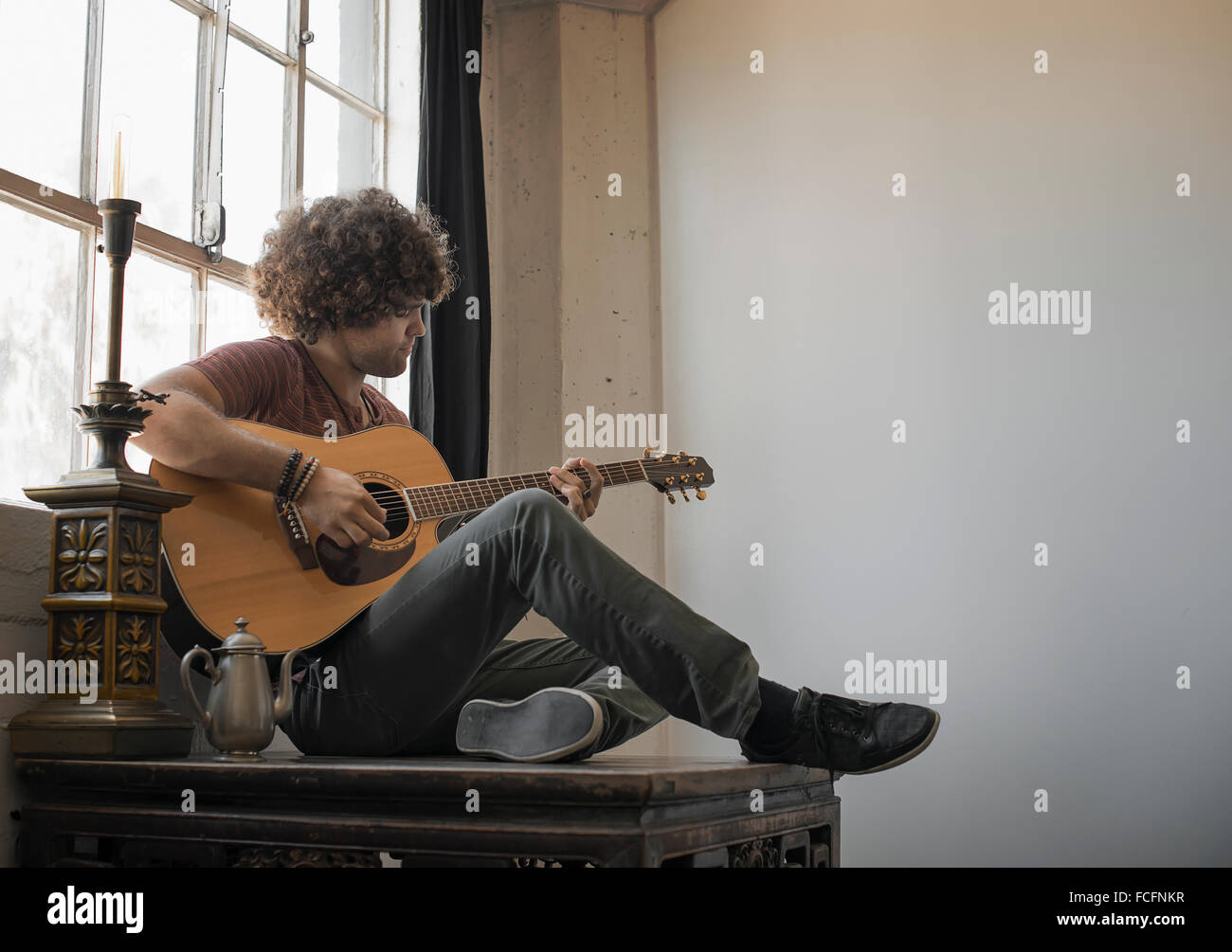 Loft-lebendigen. Ein junger Mann, die Gitarre von einem Fenster sitzen. Stockfoto