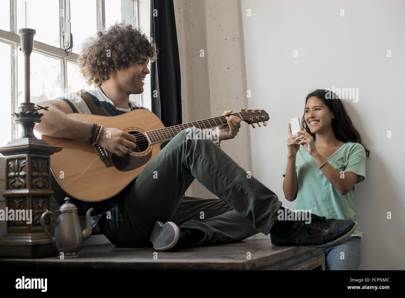 Loft Erlebnis: einen jungen Mann spielt Gitarre, ein dankbares Publikum, eine junge Frau hält eine Smartphone und ein Foto Stockfoto