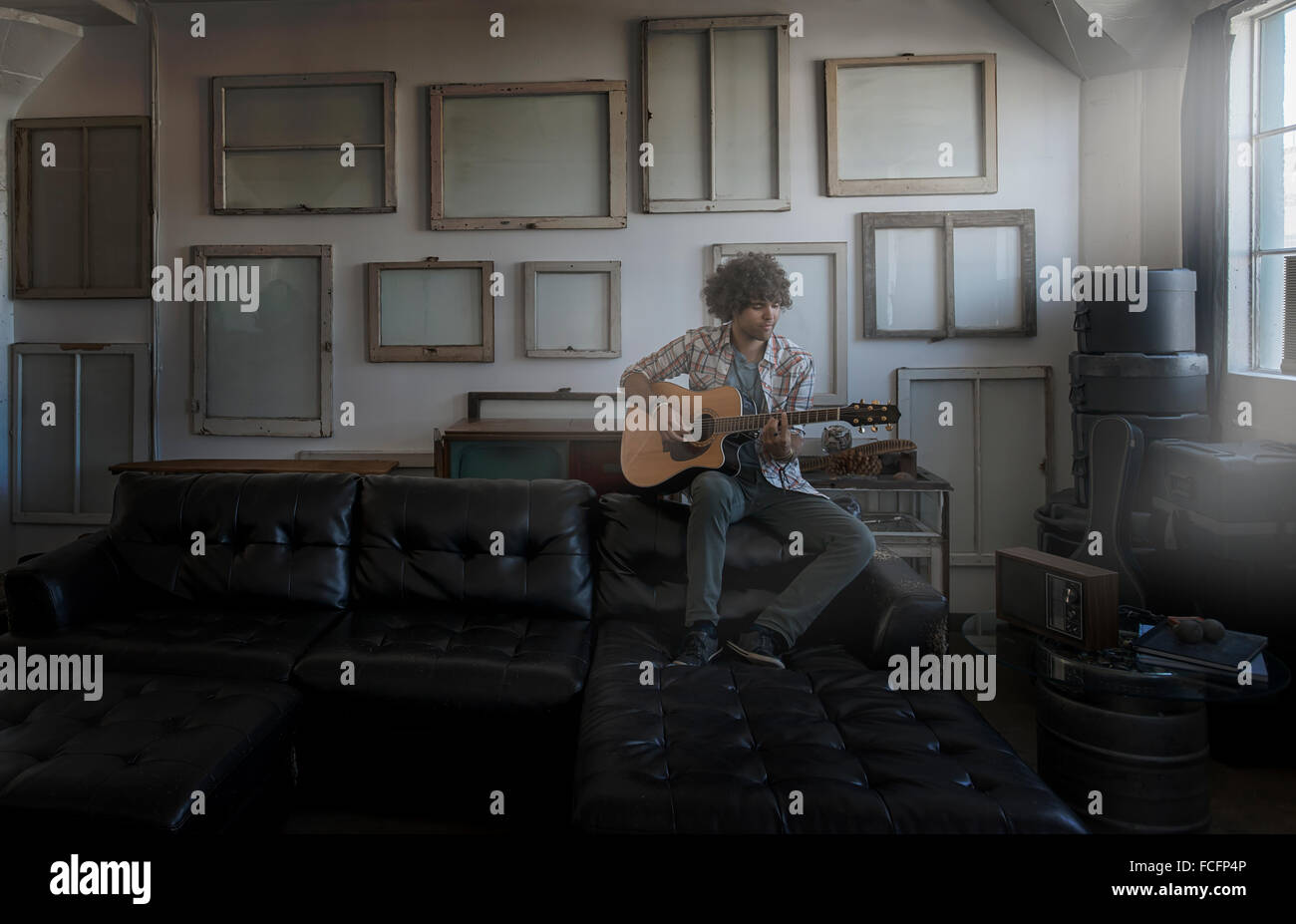 Loft-Dekor. Eine Wand gehangen mit Bilder in Rahmen, umgekehrt, um den Rücken zu zeigen. Ein Mann, eine Gitarre zu spielen. Stockfoto