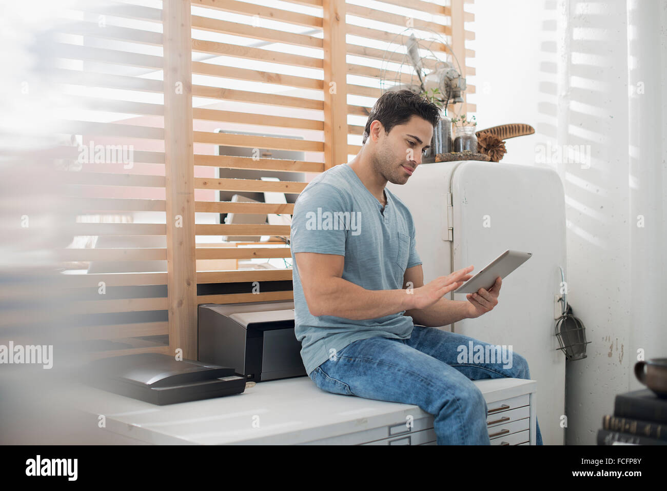 Ein Mann sitzt auf einem Tisch mit einem digital-Tablette. Stockfoto