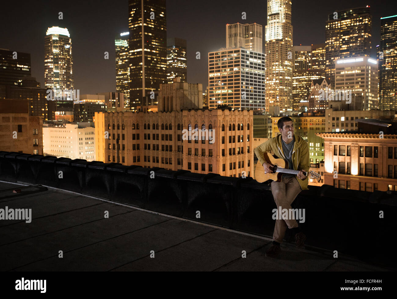 Ein Mann auf einem Dach in der Nacht, eine Gitarre zu spielen. Stockfoto