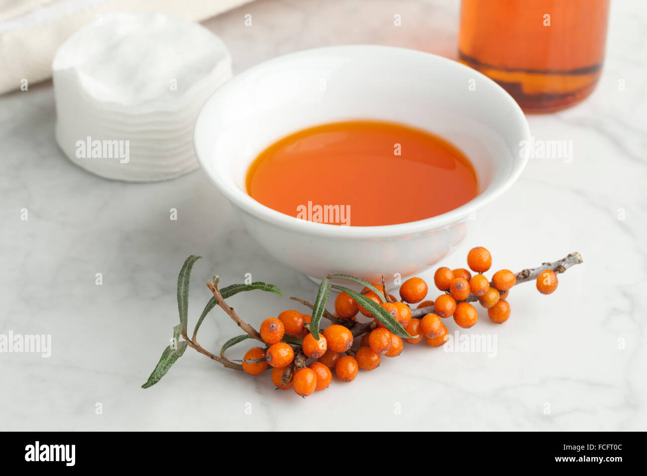 Schale mit Sanddornöl mit einem Zweig des gemeinsamen Sanddorn Stockfoto