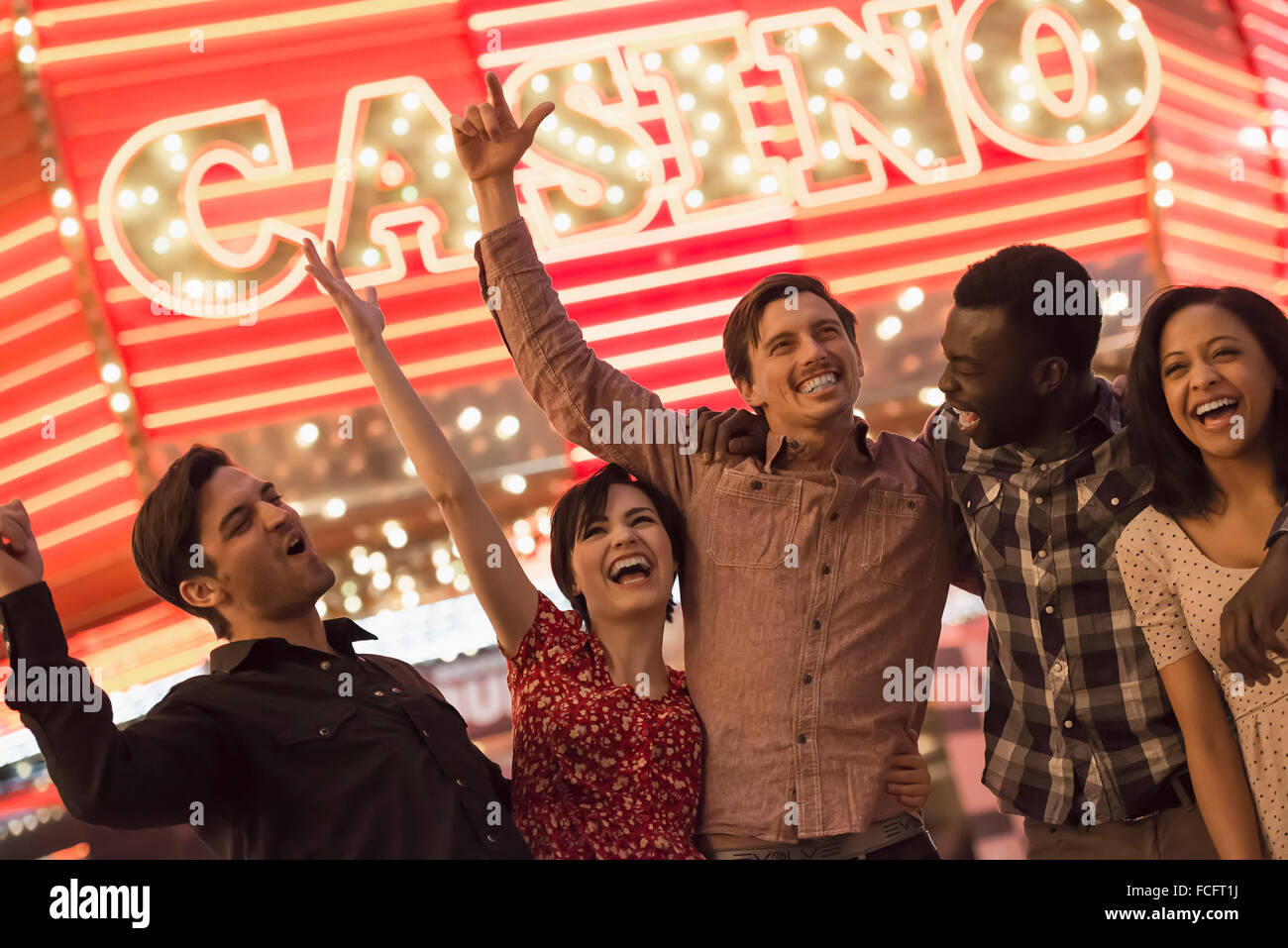 Eine Gruppe von Menschen unter einer hellen Leuchtreklame Casino. Stockfoto