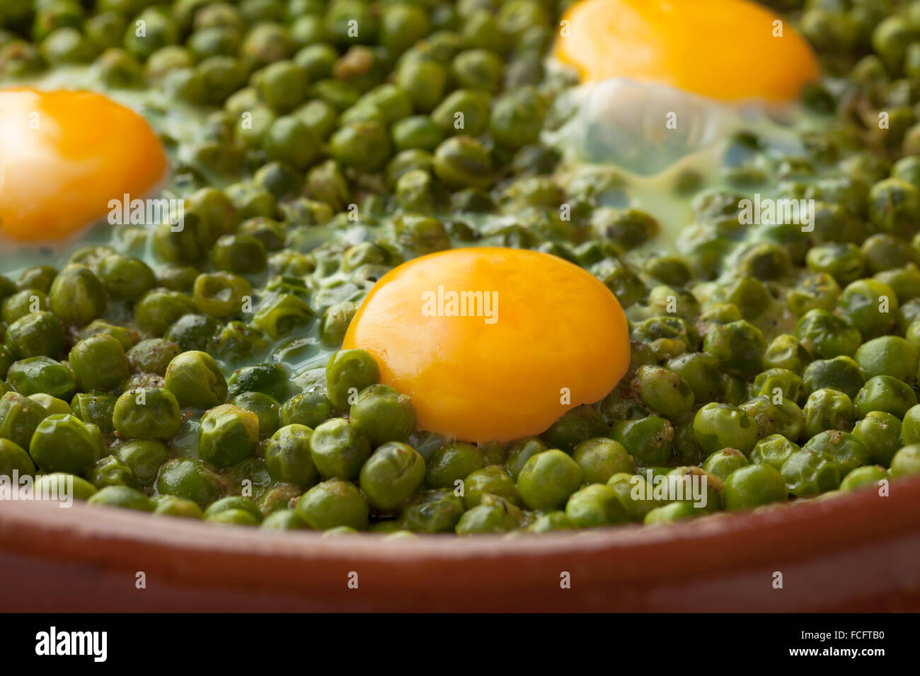 Marokkanische Tajine mit grünen Erbsen und Sonnenseite Eier hautnah Stockfoto