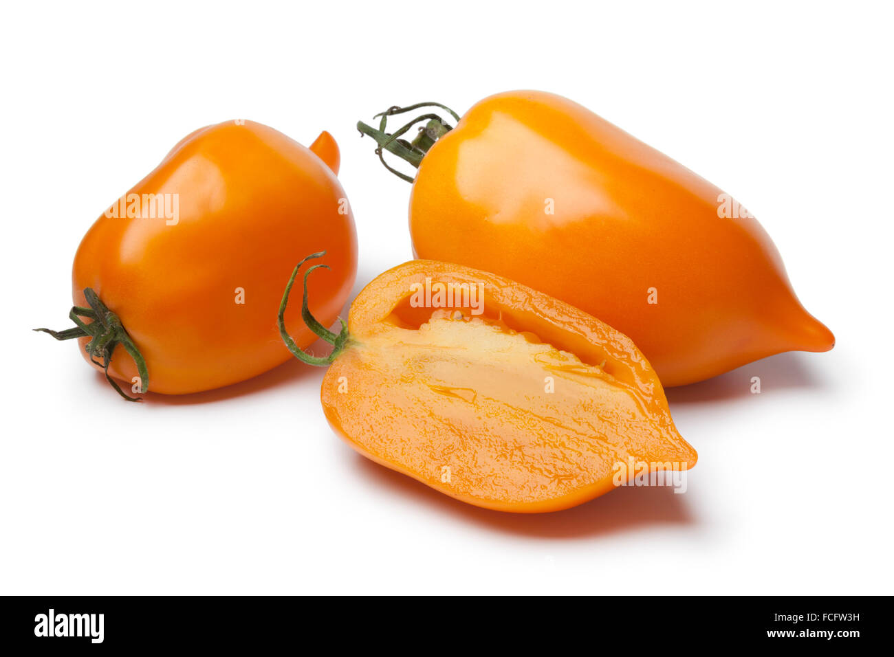 Ganze und halbe frische orange Paprika-Tomaten auf weißem Hintergrund Stockfoto