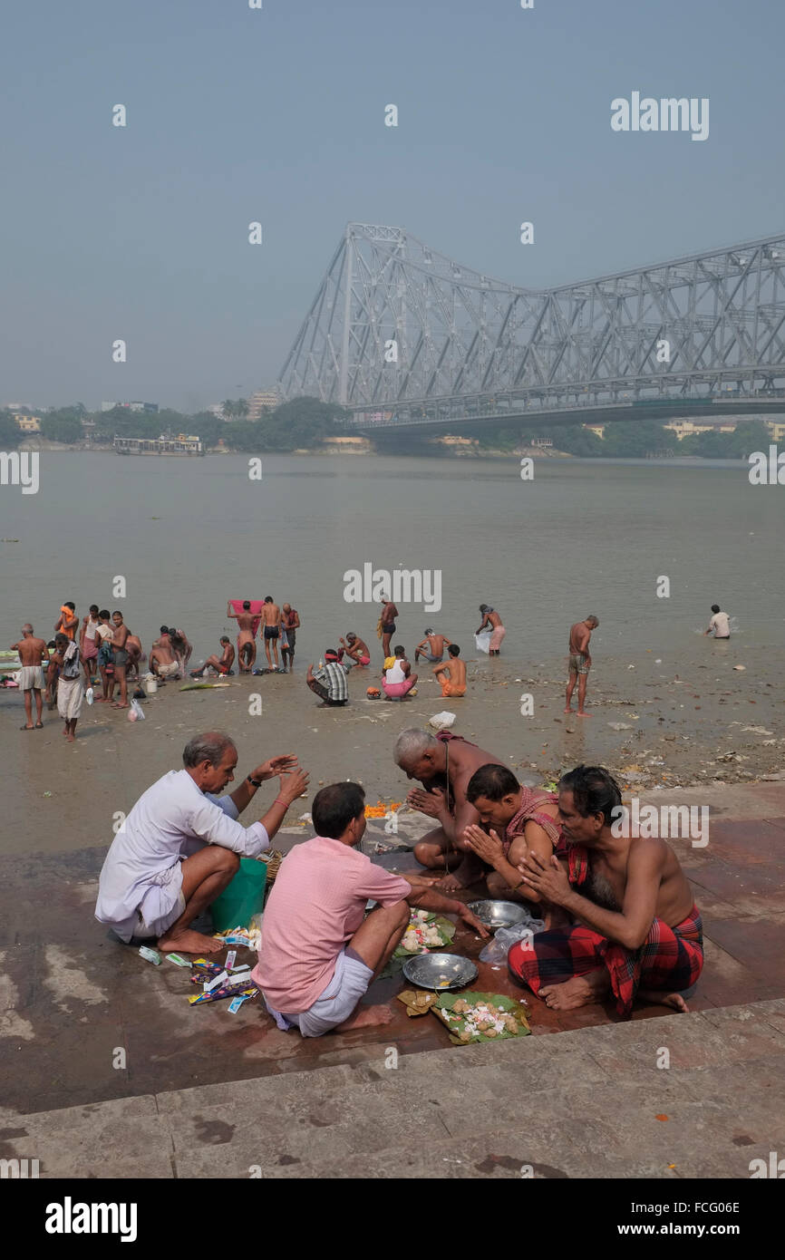 Männer, die durch den Fluss Hooghly beten in der Nähe von Howrah Bridge, Kolkata (Kalkutta), West Bengal, Indien. Stockfoto