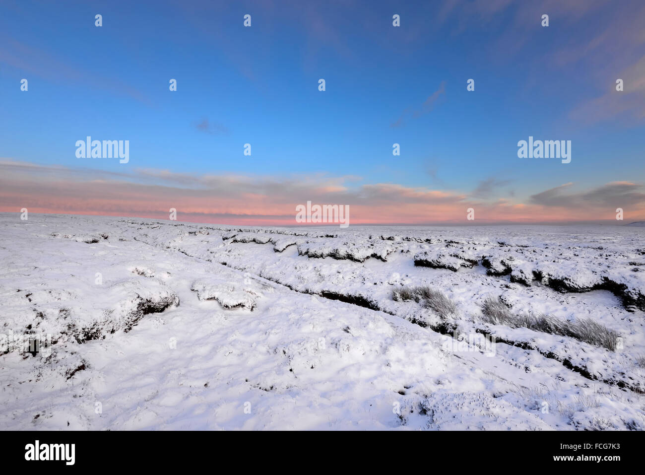 Verschneite Moorlandschaft neben der Pennine Way über Glossop in Derbyshire auf eine atemberaubende Winterlandschaft am Abend bei Sonnenuntergang. Stockfoto