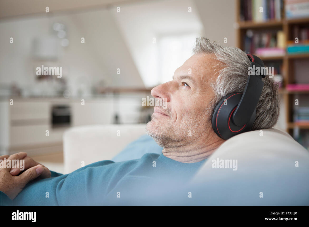 Entspannter Mann zu Hause tragen von Kopfhörern Musik hören Stockfoto