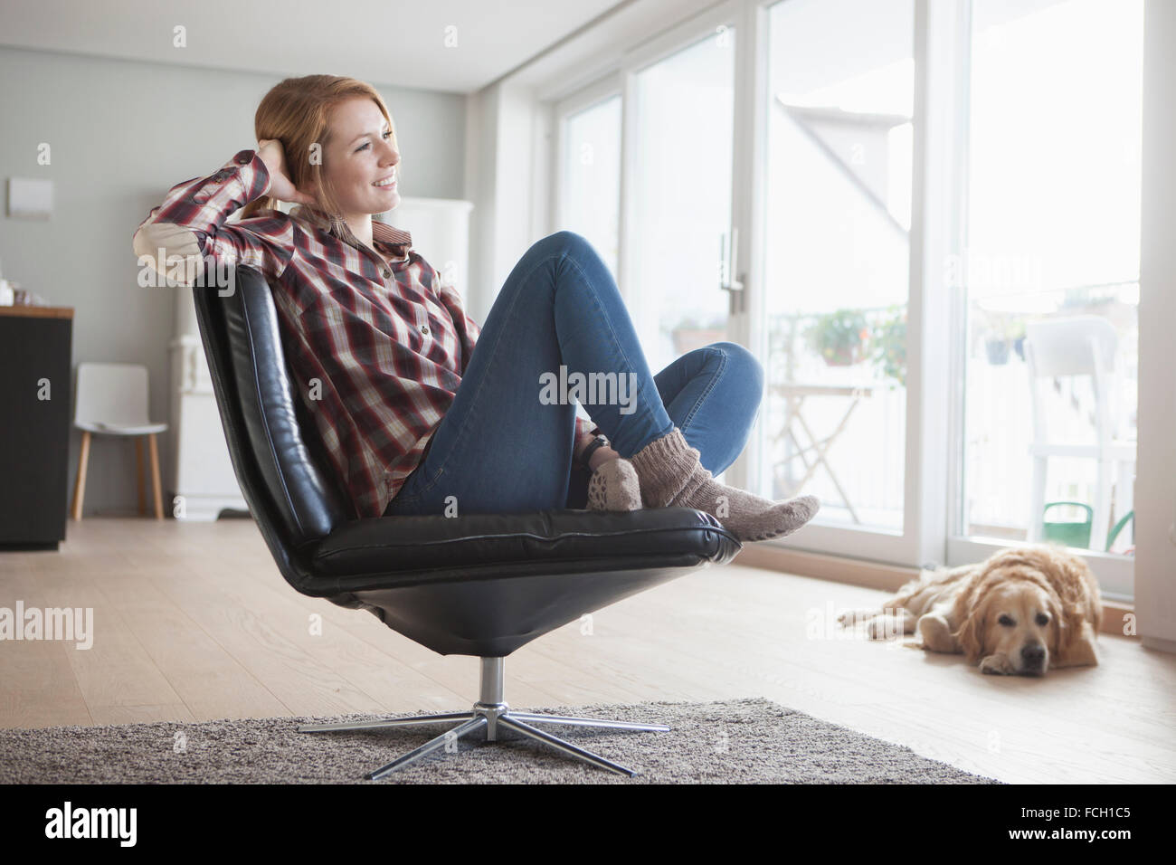 Junge Frau auf einem Ledersessel zu Hause entspannen Stockfoto