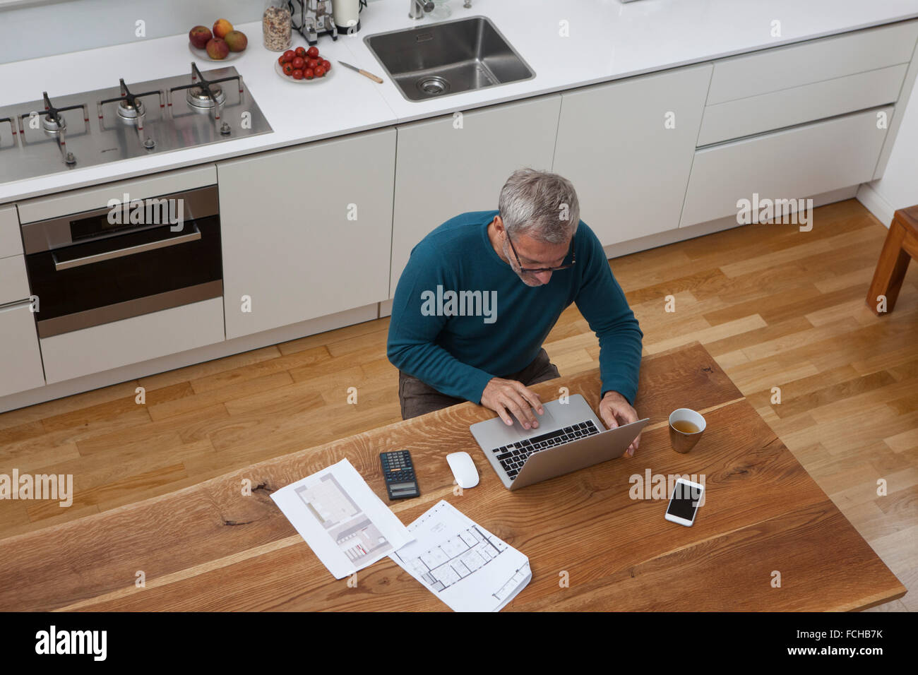 Reifer Mann in der Küche Bauplan mit laptop Stockfoto