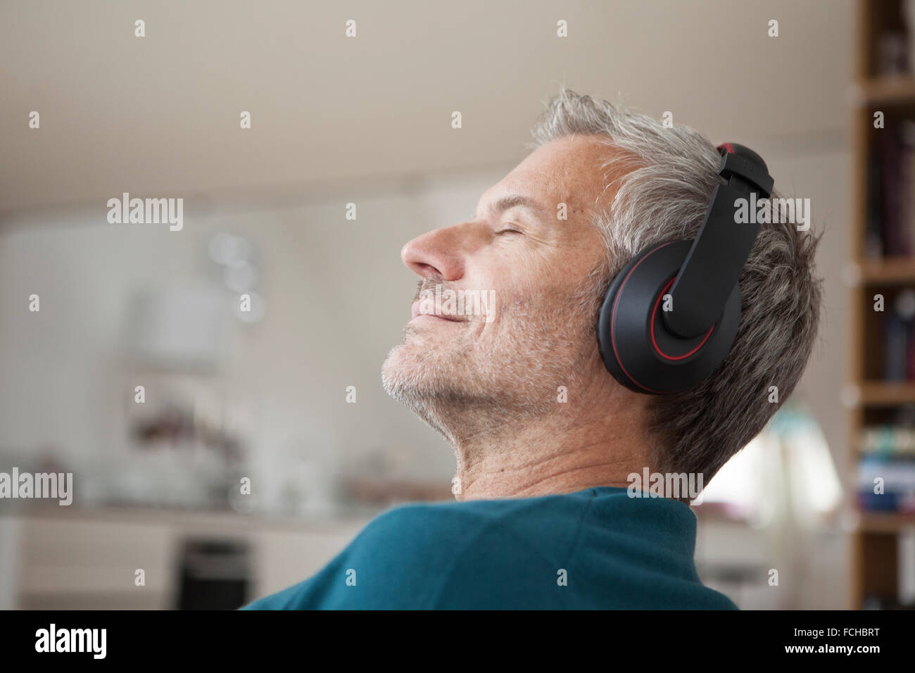 Entspannter Mann zu Hause tragen von Kopfhörern Musik hören Stockfoto