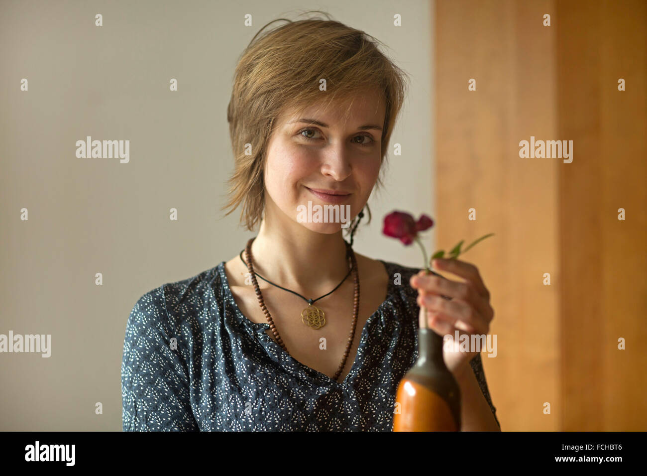 Porträt der lächelnde junge Frau Blumenvase Stockfoto