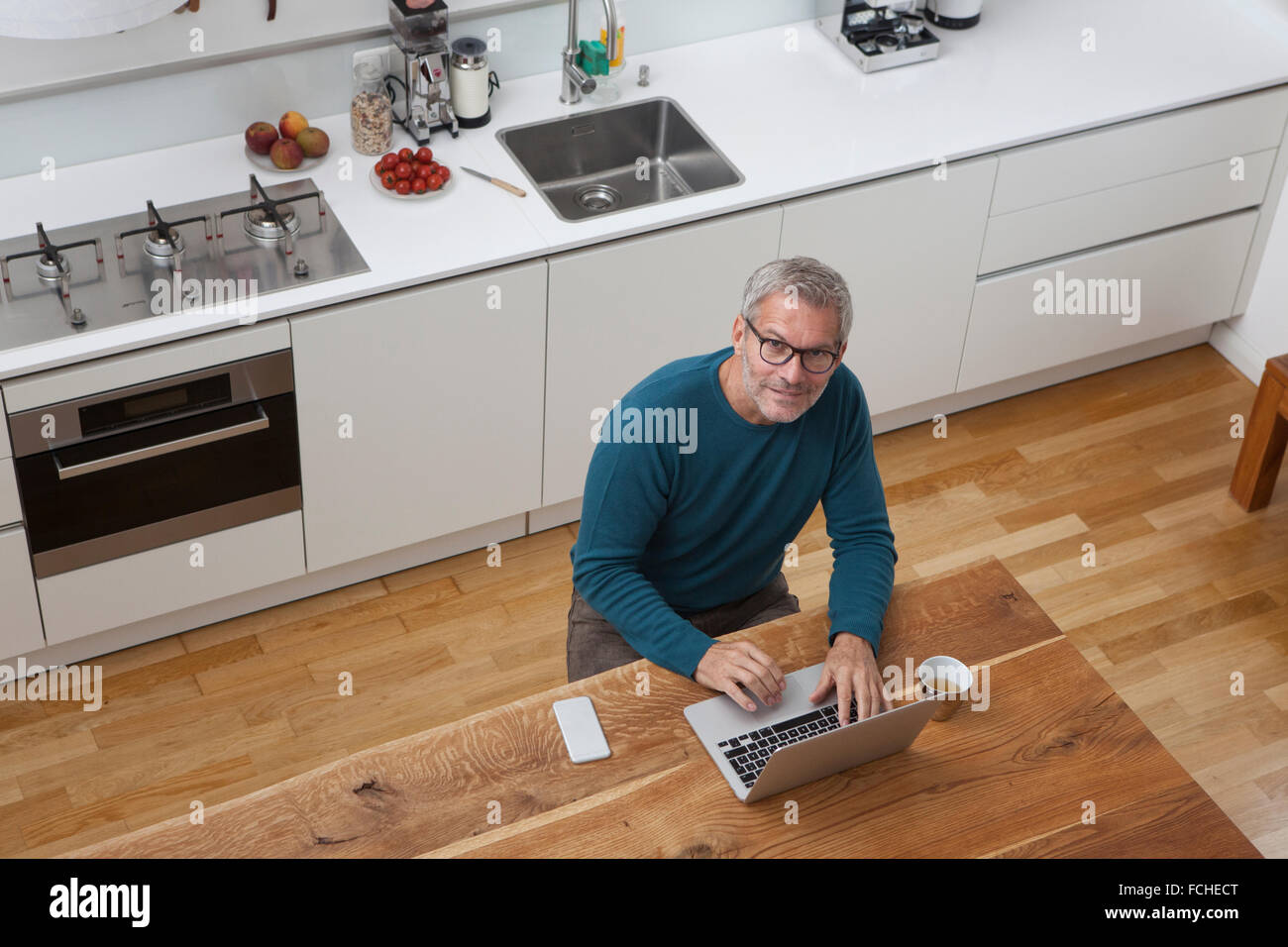 Reifer Mann in der Küche mit laptop Stockfoto