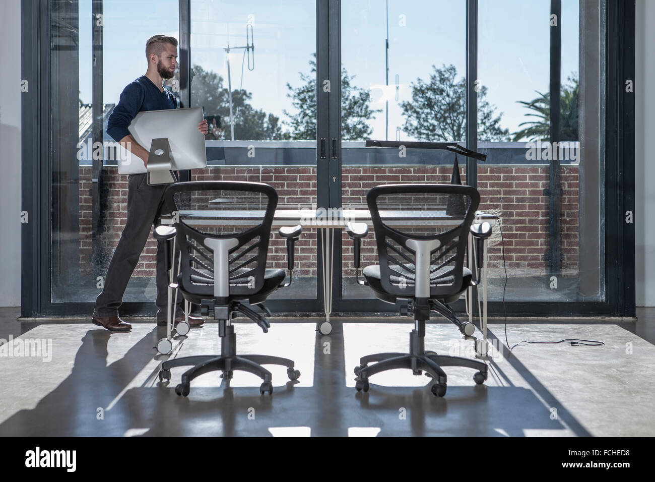 Mann mit Computer-Monitor in leeres Büro Stockfoto