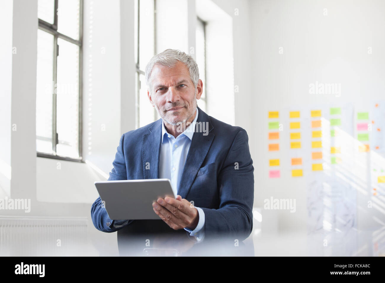 Porträt der Geschäftsmann im Amt halten digital-Tablette Stockfoto