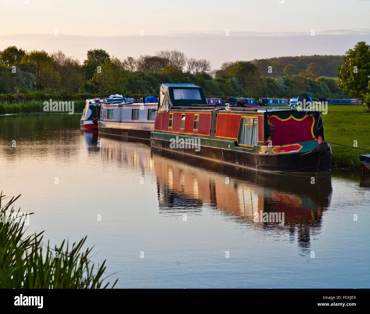 Eine Reihe von Kanalboote an einem britischen Kanal im Wasser gespiegelt. Stockfoto