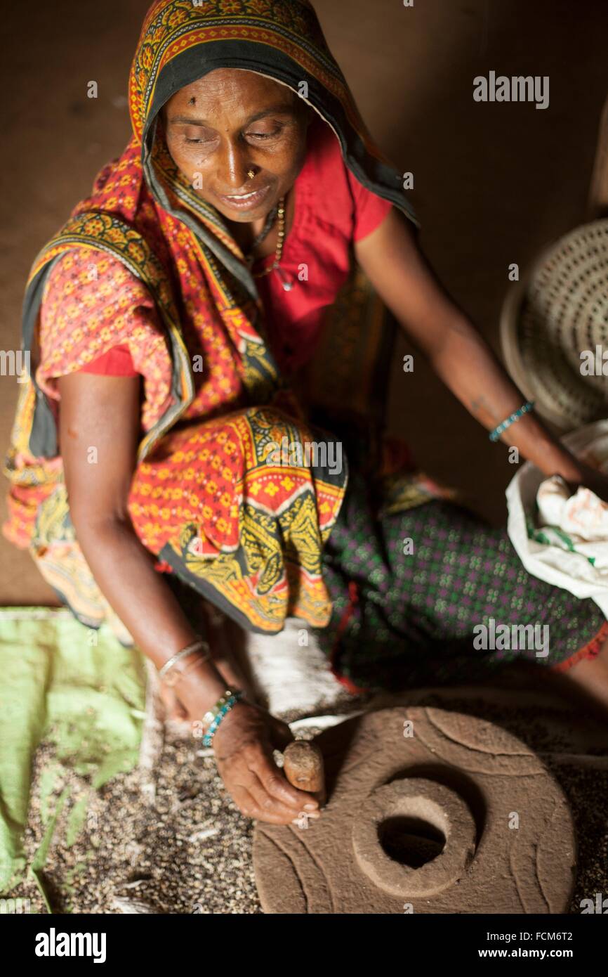 Frau des Stammes der Bhil Mahlen von Getreide in Indien Stockfoto
