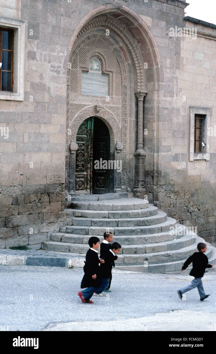 Türkische Schule Jungen führen vorbei an einer Madrasa oder Medrese Schule in Mustafapasa, Nevsehir, Ürgüp, Cappadicia, Türkei Stockfoto
