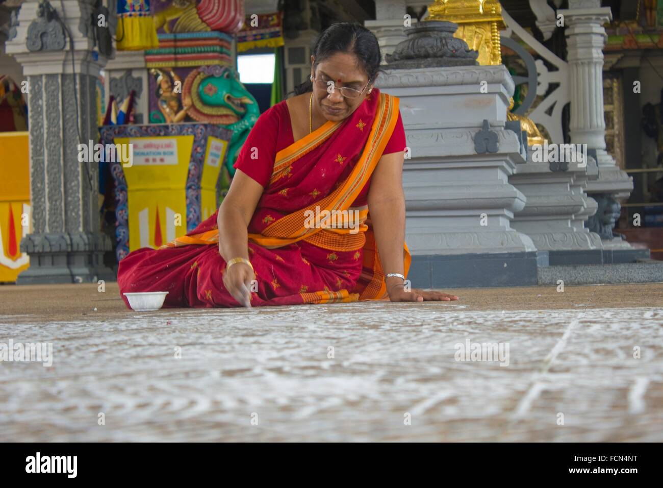 Ältere Indianerin zeichnen Kolam auf dem Boden in Singapur. Tempel. Es