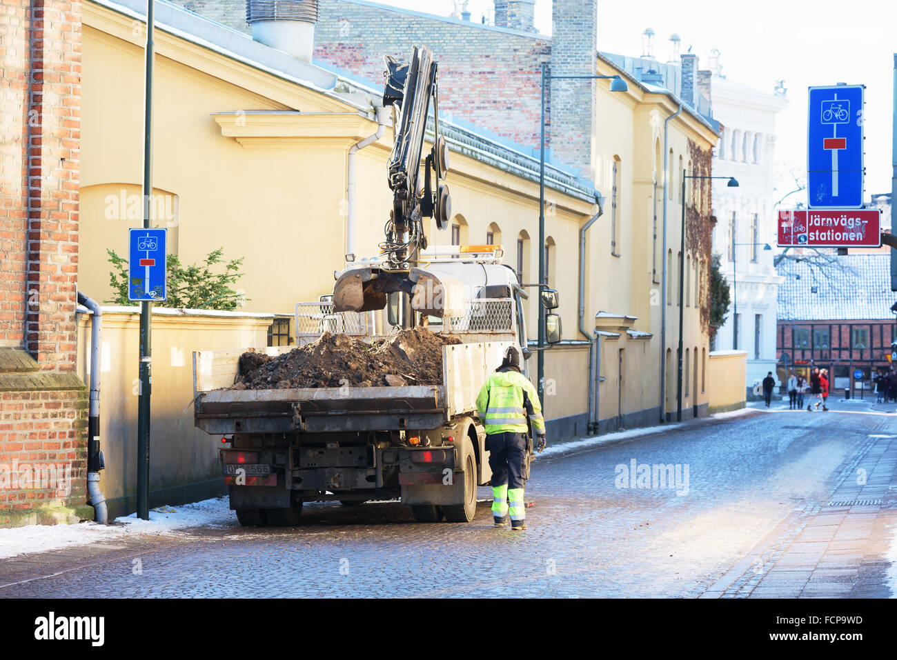 Lund, Schweden - 21. Januar 2016: Ein Arbeitnehmer hat nur etwas Erde von der anderen Seite einer Mauer und zu Fuß neben seinen LKW t gesammelt Stockfoto