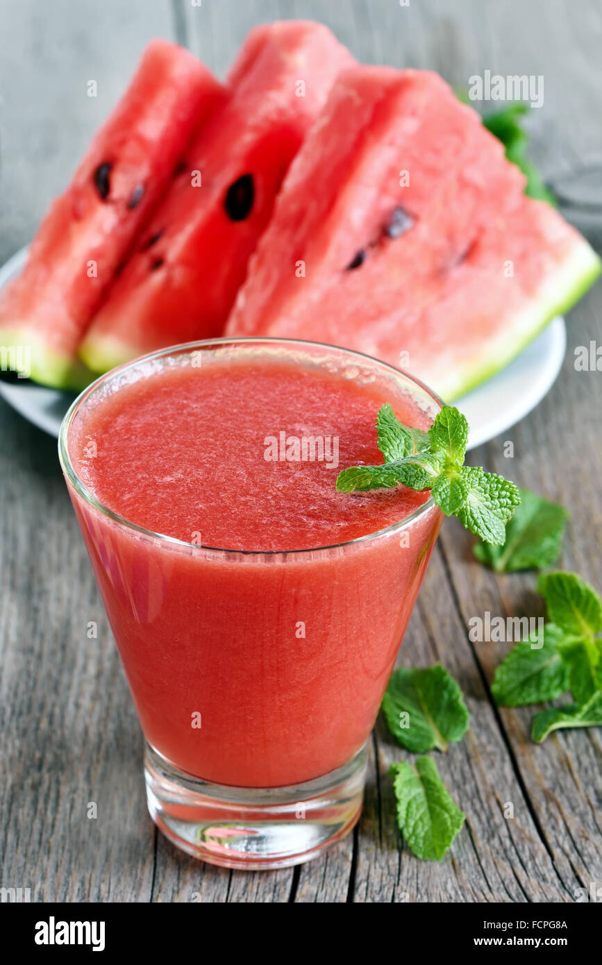 Wassermelonensaft im Glas und in Scheiben schneiden, auf hölzernen Hintergrund Stockfoto
