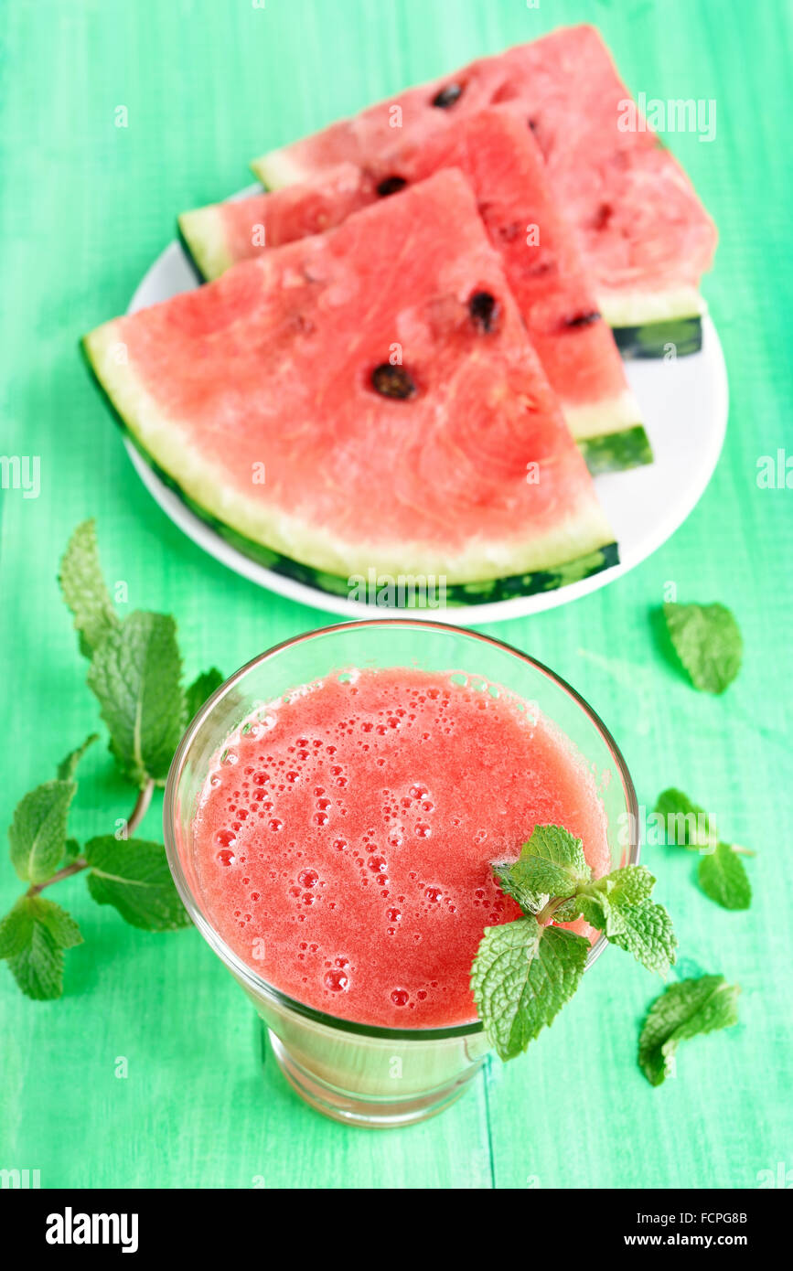 Wassermelonen-Smoothie im Glas und in Scheiben schneiden, auf grünen hölzernen Hintergrund, Ansicht von oben Stockfoto