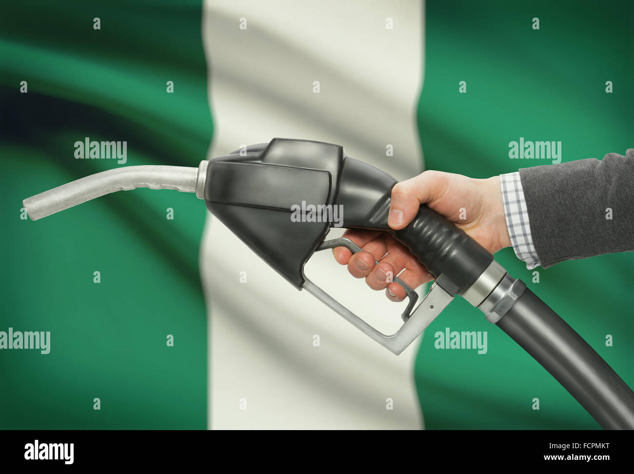 Kraftstoff Pumpe Düse in der hand mit Flagge auf Hintergrund - Nigeria Stockfoto