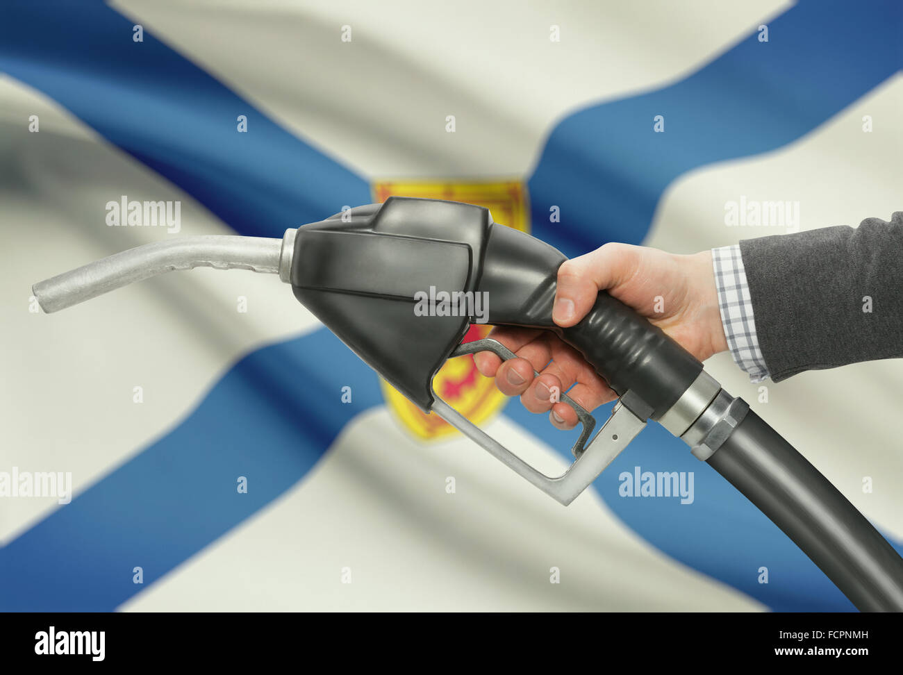 Kraftstoff Pumpe Düse in der hand mit kanadischen Provinzen und Territorien Fahnen auf Hintergrund - Nova Scotia Stockfoto