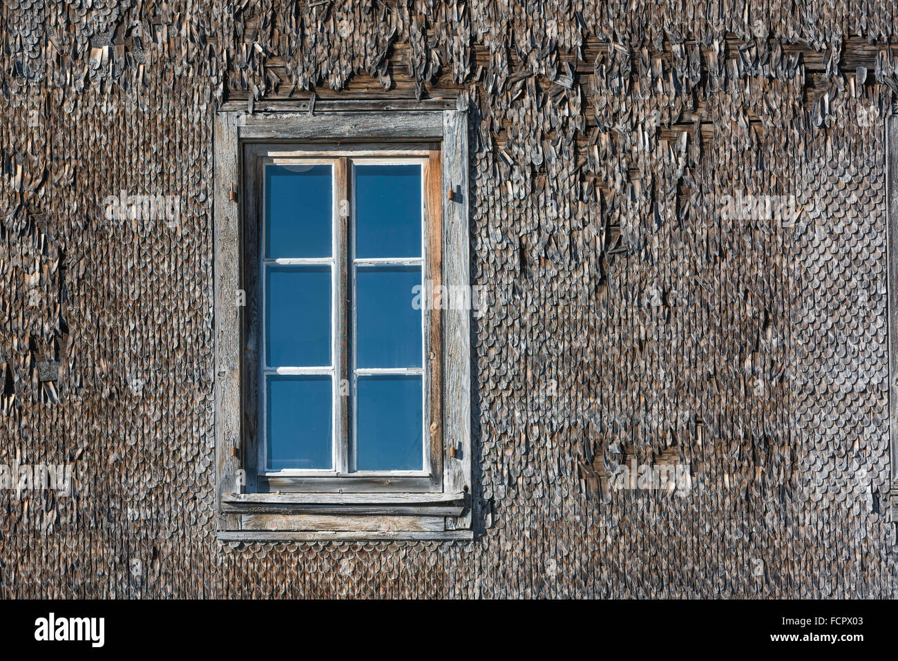 Gitter-Fenster auf eine weatherboarded Fassade eine alte, verwitterte Holzfassade. Alte hölzerne Schindeln. Stockfoto