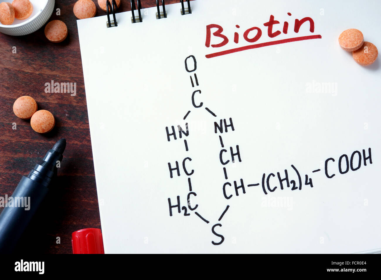 Notizblock mit Biotin und Pillen auf dem Tisch. Stockfoto