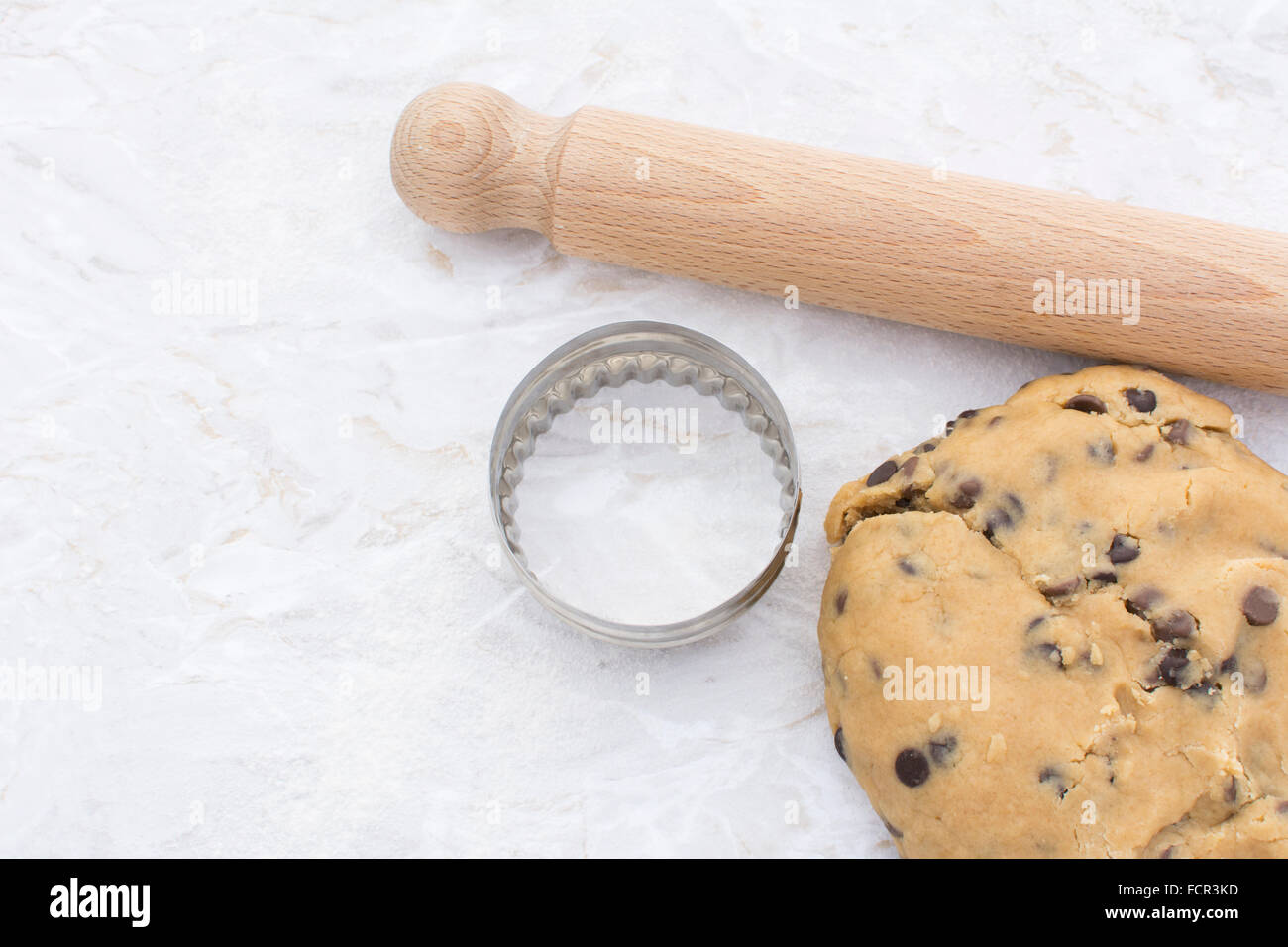 Chocolate Chip Cookie-Teig mit hölzernen Nudelholz und runden Ausstecher auf einer bemehlten Küche Arbeitsplatte Stockfoto
