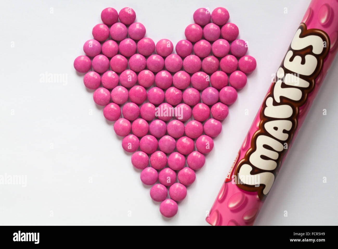 Rosa Nestle Smarties in der Form eines Herzens mit Rohr auf weißem Hintergrund angeordnet - für Valentines Tag bereit, Valentinstag Stockfoto