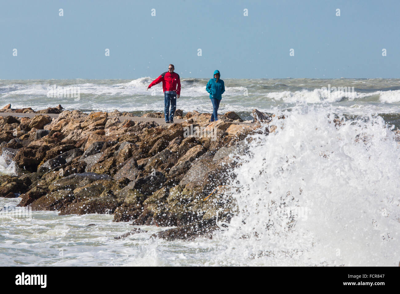 Frau und Mann zu Fuß Hund mit Golf von Mexiko Sturmwellen am südlichen Steg in Venice Florida Stockfoto