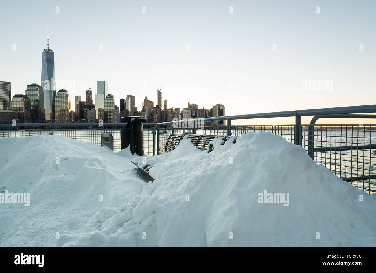 Jersey City, USA. 24. Januar 2016. Eine Bank am Wasser bedeckt fast vollständig im Schnee mit der NYC Skyline im Hintergrund. Die Sonne geht über Jersey City, wo die Jonas Blizzard die Straßen, im Schnee Credit verlassen hat: Elizabeth Wake/Alamy Live News Stockfoto