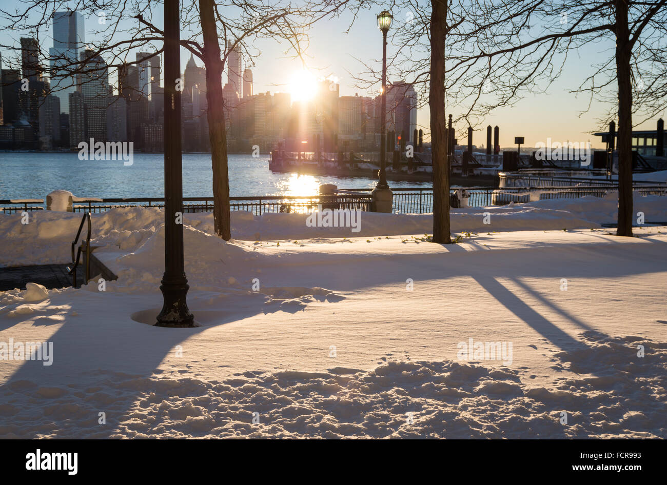 Die Sonne scheint durch die Skyline von NYC beleuchtet den Schnee im Sturm Jonas am Jersey City Wasser gelassen. Stockfoto