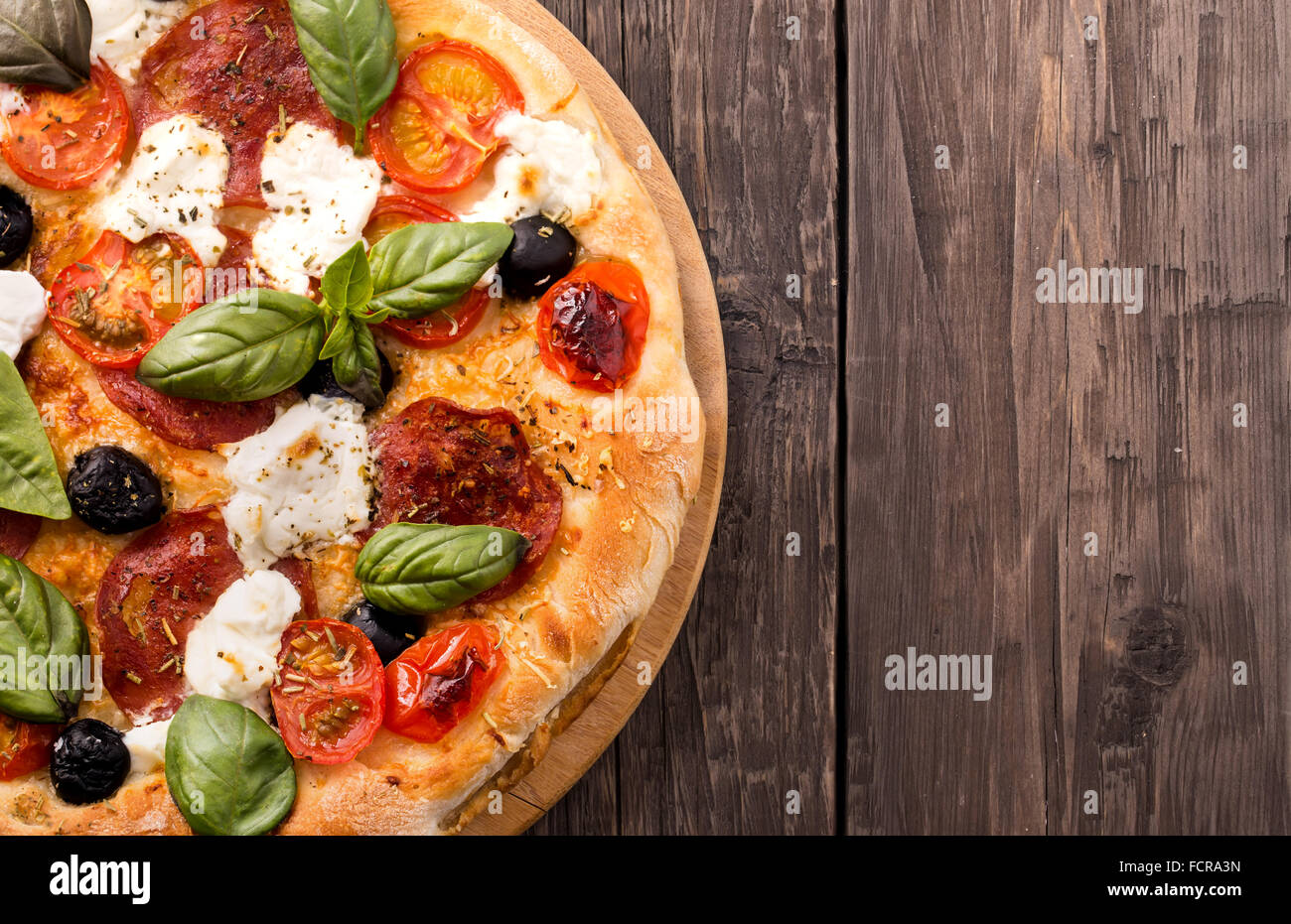 Rustikale Pizza mit Salami, Mozzarella, Oliven und Basilikum Draufsicht mit Textfreiraum Stockfoto