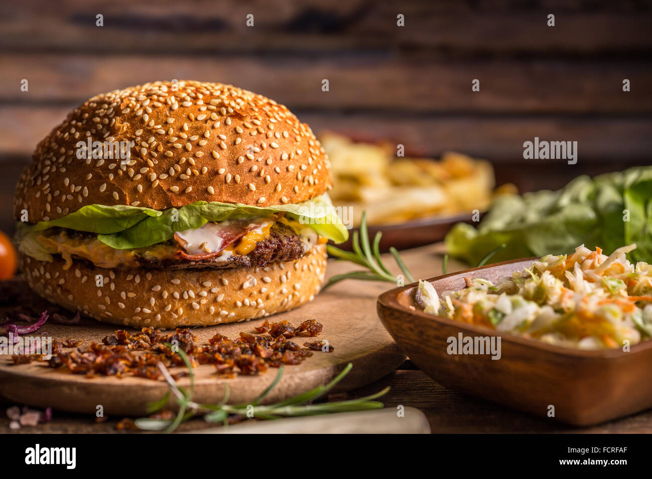 Beef-Burger im Brötchen mit getrockneten Zwiebeln und Salat Stockfoto