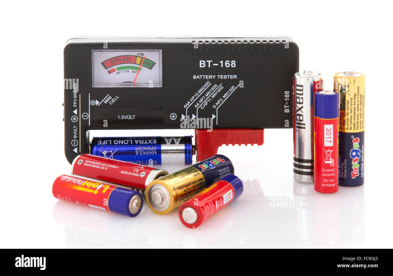 Batterie-Tester mit Sortiment von Trockenbatterien zu Testzwecken auf weißem Hintergrund Stockfoto