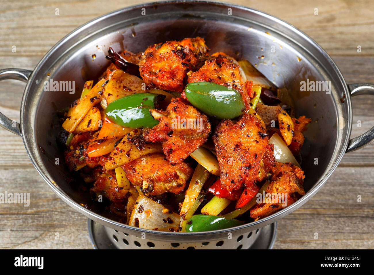 Hoher seitlicher Blick auf einem Edelstahl Kochtopf gefüllt gebratenes Huhn und Gemüse auf rustikalen Holz. Stockfoto