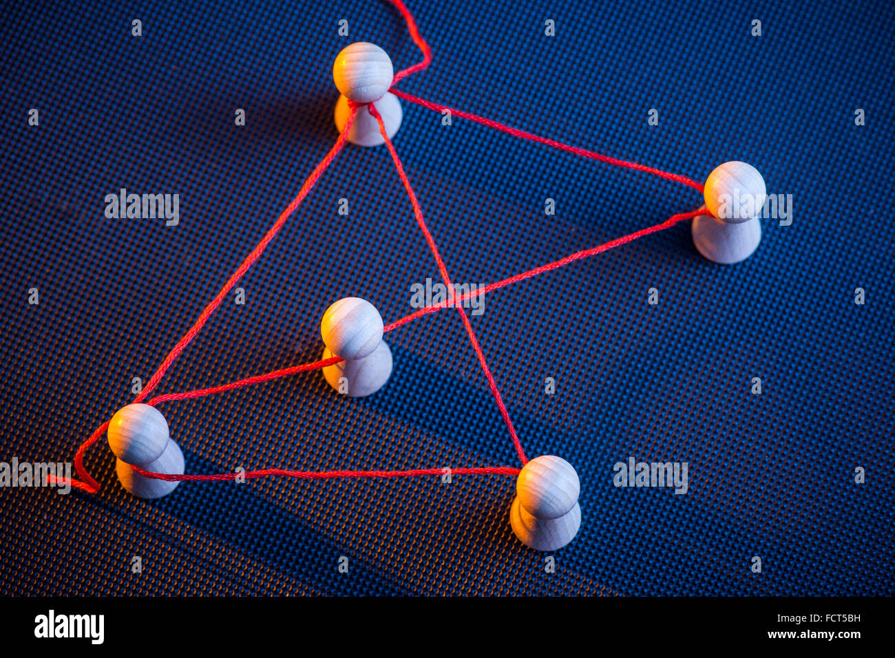 erhöhte Detailansicht mit roter Faden im Zusammenhang mit Ludo Spielfiguren auf dunklen Nieten Oberfläche auf den Seiten Licht in rot und blau Stockfoto